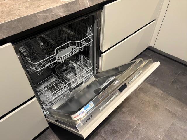 Zandkleurige greeploze hoekkeuken voorzien van luxe Bosch apparaten