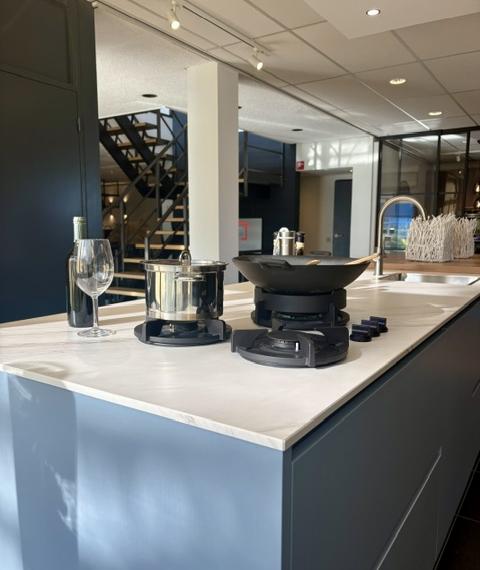 Moderne keuken met een lichtblauw eiland en keramiek marmer look blad, gecombineerd met zwarte hoogglans kasten