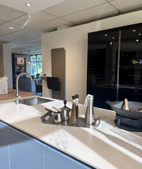 Moderne keuken met een lichtblauw eiland en keramiek marmer look blad, gecombineerd met zwarte hoogglans kasten