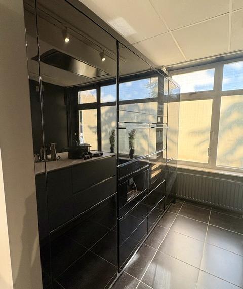 Moderne keuken met een lichtblauw eiland en keramiek marmer look blad, gecombineerd met zwarte hoogglans kasten