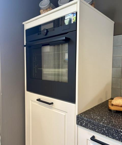 Klassieke keuken met een mat wit gelakt kaderdeur  en een zwart composiet blad