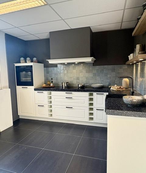 Klassieke keuken met een mat wit gelakt kaderdeur  en een zwart composiet blad