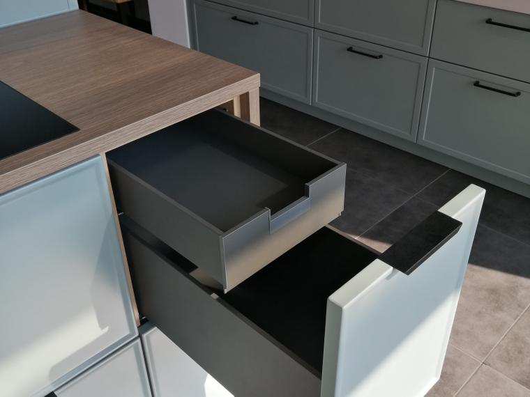 Formschöne Musterküche von Häcker, mit schwarzem Bügelgriff und Griffleiste, ohne Geräte
