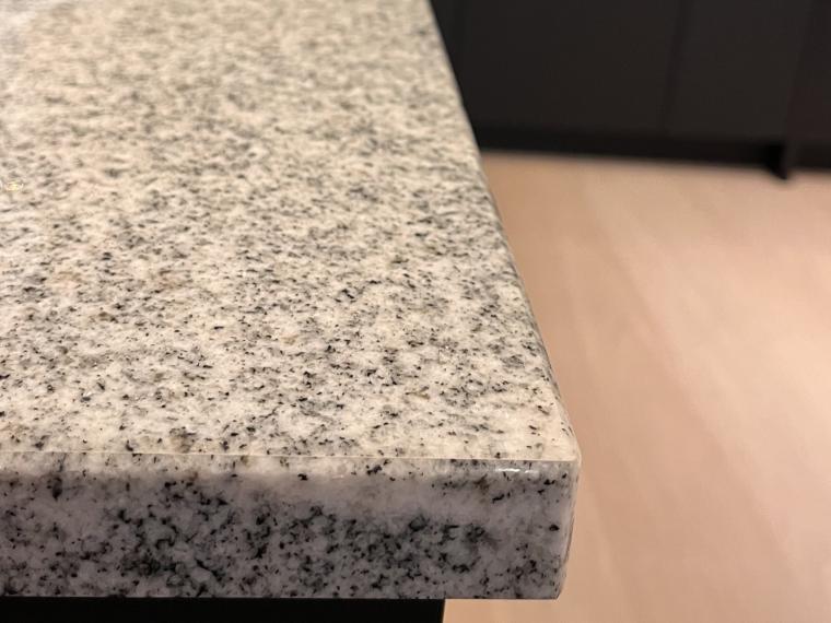 Zwarte L-vormige showroomkeuken met granieten werkblad