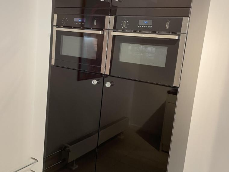 Moderne hoogglans lak keuken in speelse opstelling met granieten werkblad.