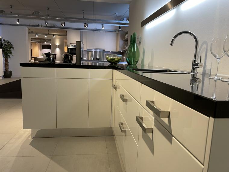 Moderne hoogglans lak keuken in speelse opstelling met granieten werkblad.