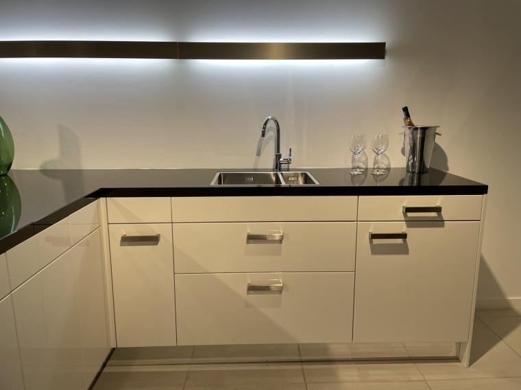 Moderne hoogglans lak keuken in speelse opstelling met granieten werkblad.