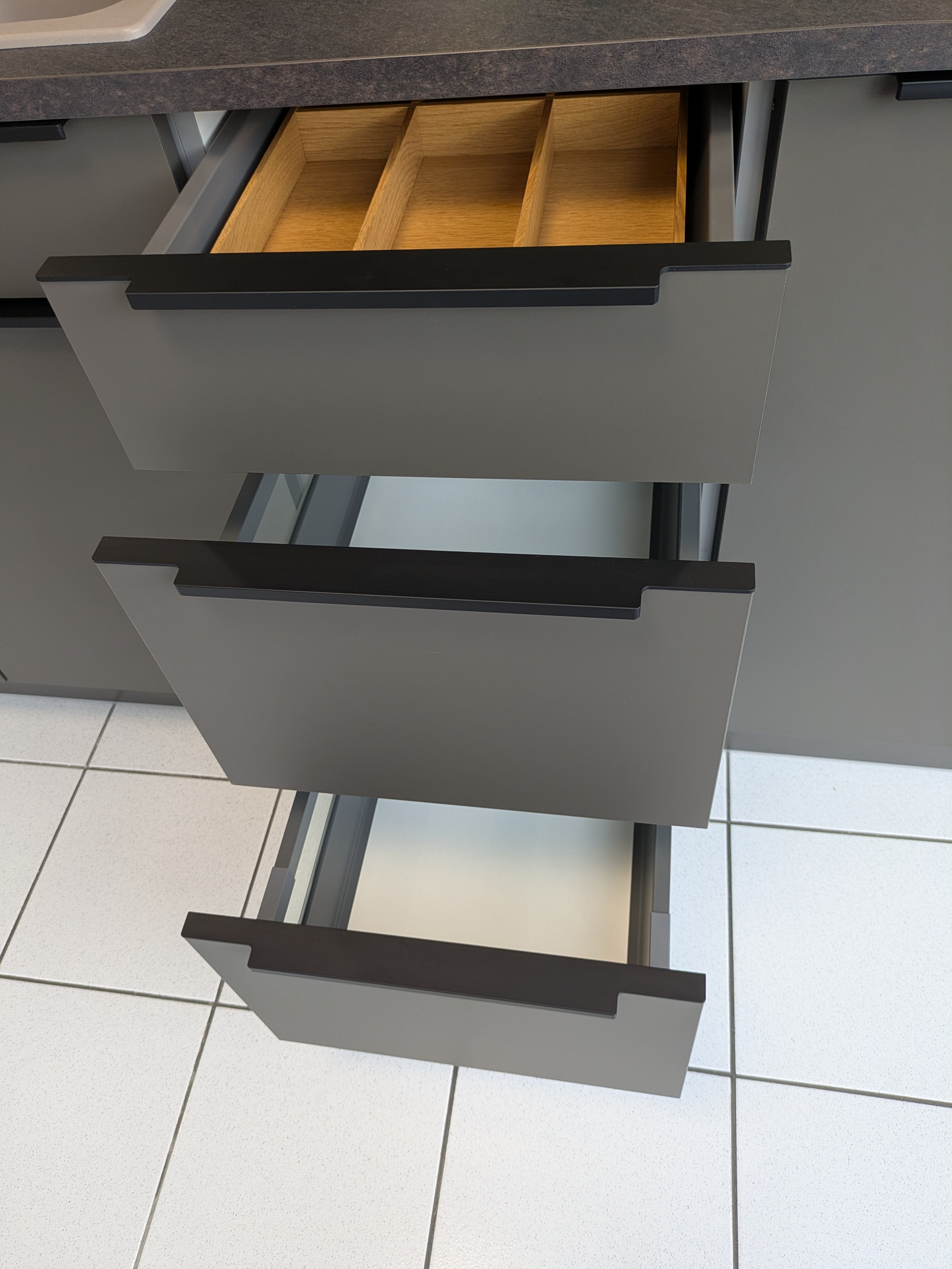Tolle, dunkle und moderne L-Küche mit schwarzen Griffleisten und Rauchglas