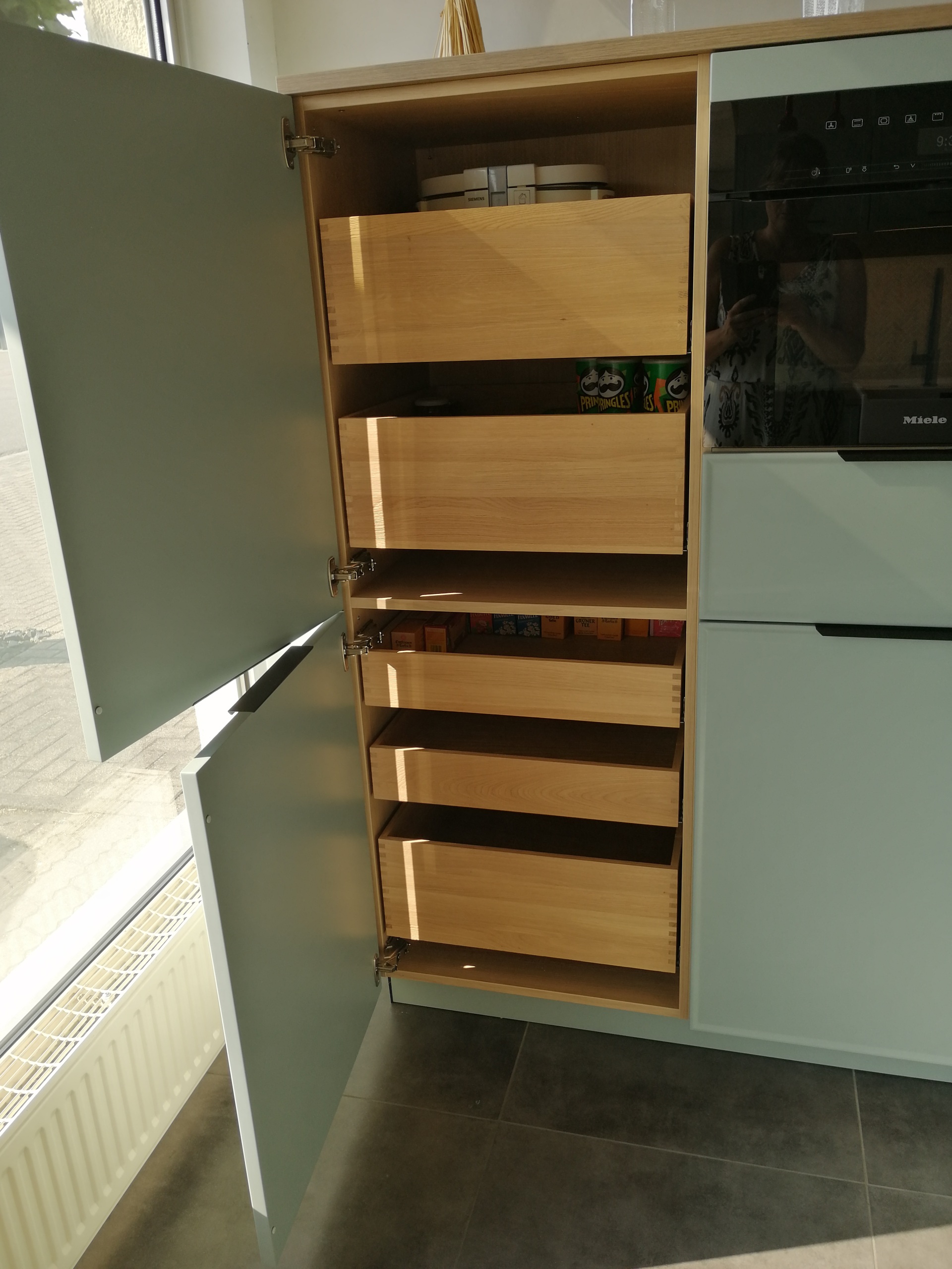 Formschöne Musterküche von Häcker, mit schwarzem Bügelgriff und Griffleiste, ohne Geräte