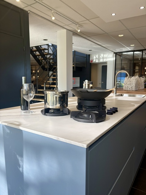 Moderne keuken met een lichtblauw eiland en keramiek marmer look blad, gecombineerd met zwarte hoogglans kasten