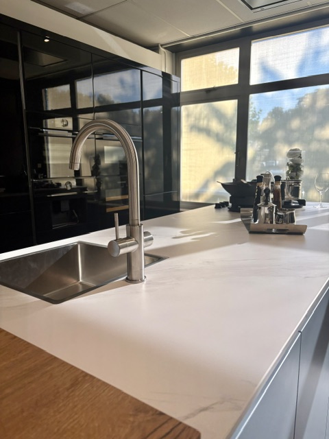 Moderne keuken met een lichtblauw eiland en keramiek marmer look blad, gecombineerd met zwarte hoogglans kasten