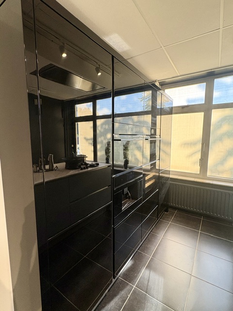 Moderne keuken met een lichtblauw eiland en keramiek marmer look blad, gecombineerd met zwarte hoogglans kasten