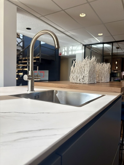 Moderne keuken met een lichtblauw eiland en keramiek marmer look blad, gecombineerd met zwarte hoogglans kasten