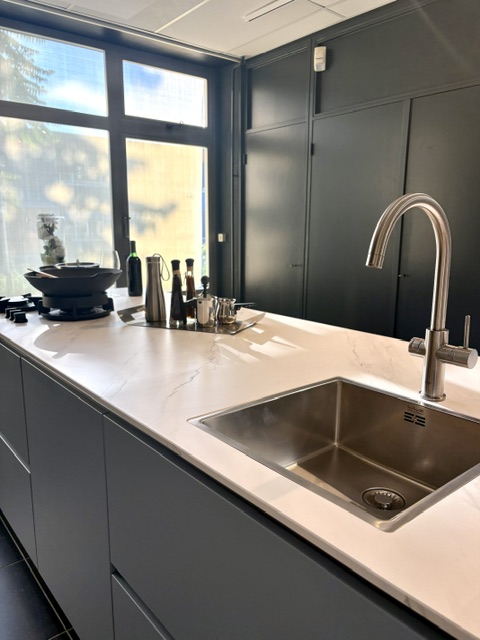 Moderne keuken met een lichtblauw eiland en keramiek marmer look blad, gecombineerd met zwarte hoogglans kasten