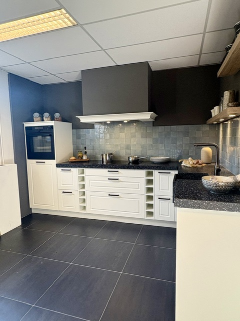 Klassieke keuken met een mat wit gelakt kaderdeur en een zwart composiet blad