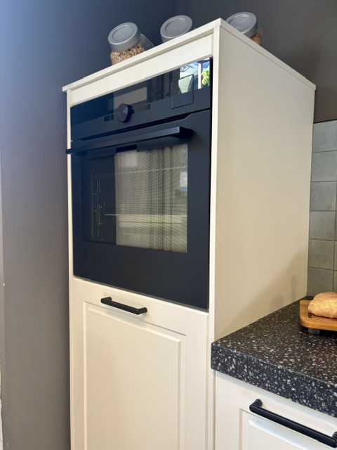 Klassieke keuken met een mat wit gelakt kaderdeur en een zwart composiet blad
